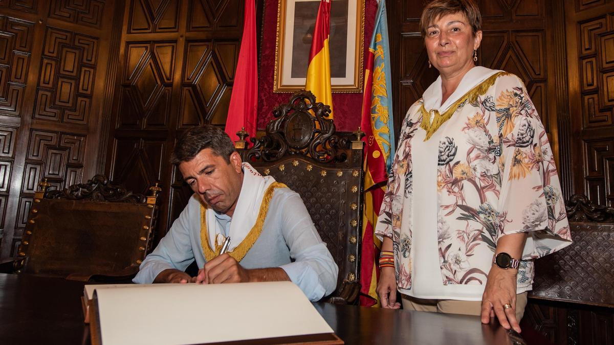 El president, Carlos Mazón, firma en el libro de honor junto a la alcaldesa de Segorbe, Mari Carmen Climent.