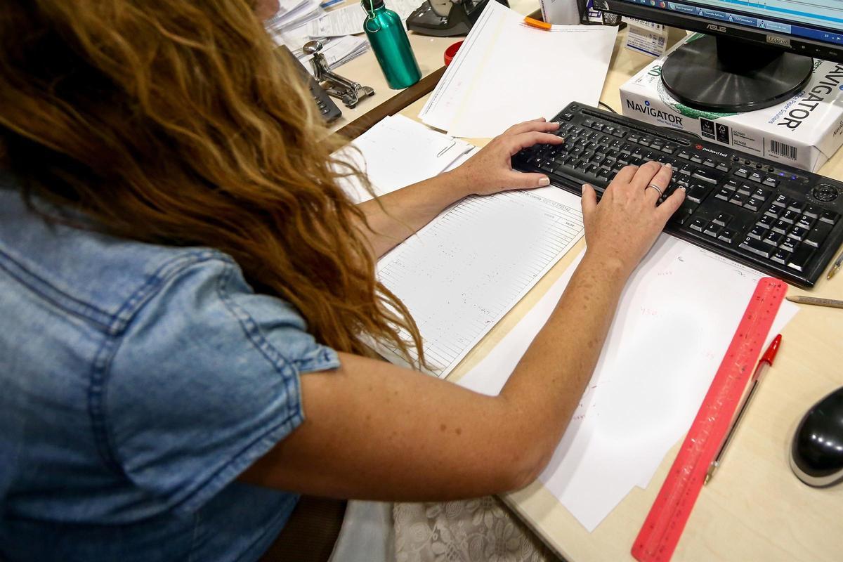 Una mujer escribe en el teclado del ordenador de su oficina.