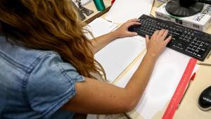 Una mujer escribe en el teclado del ordenador de su oficina.