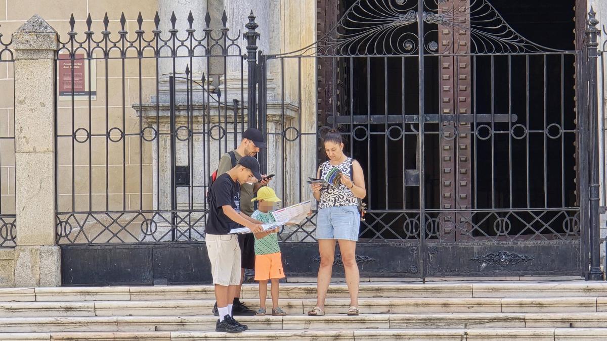 Una familia de turistas, en las escaleras de la Catedral, lee un dossier de viaje sobre Badajoz.