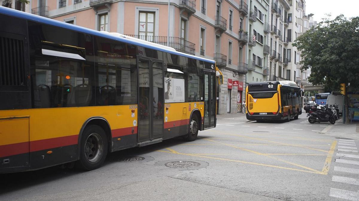 Dos autobusos entrant al carrer de Santa Eugènia, des de la plaça Marquès de Camps
