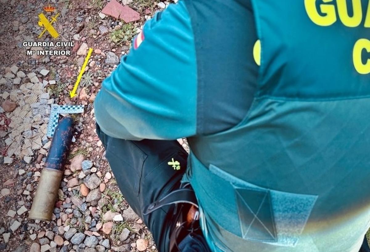 Un Guardia Civil con el proyectil de artillería hallado en Calamonte.