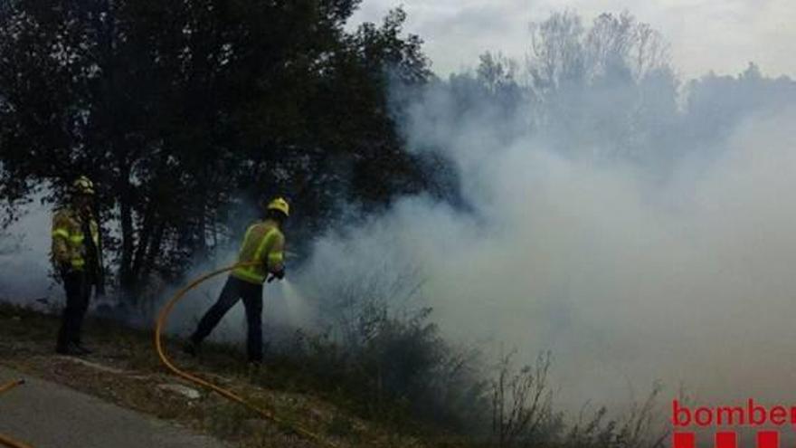 Els bombers apagant les flames a peu de la carretera de Vilopriu.