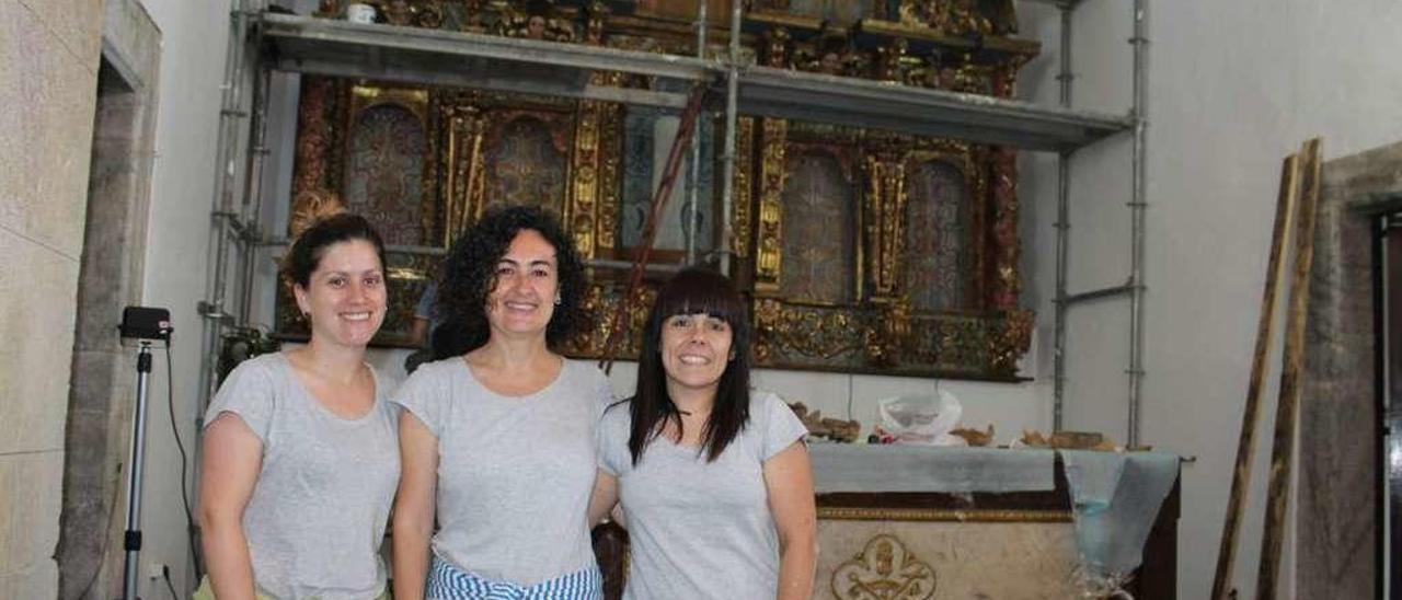 Las restauradoras Laura Rodríguez, Marta Luisa Corrada y Mónica Ruiz, ayer, junto al retablo.