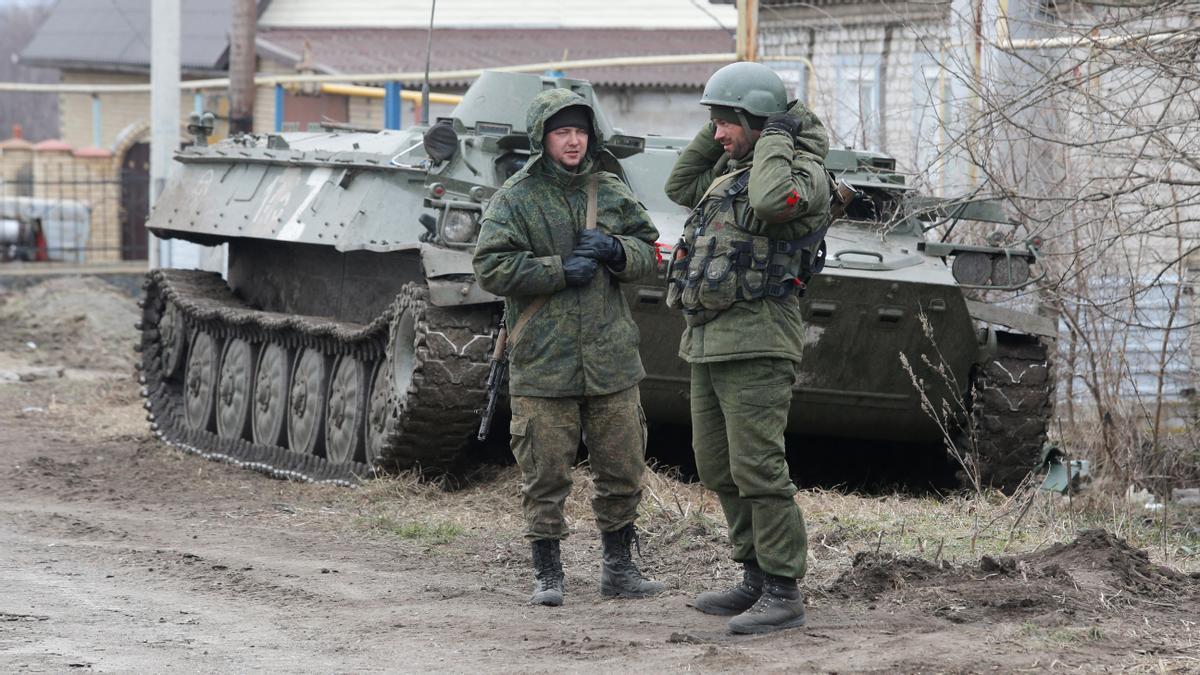 Service members of pro-Russian troops in uniforms without insignia stand next to an armoured vehicle in the separatist-controlled settlement of Buhas (Bugas), as Russia's invasion of Ukraine continues, in the Donetsk region, Ukraine March 1, 2022. REUTERS/Alexander Ermochenko