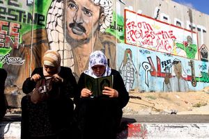 Una dona llegeix l’Alcorà davant del mur de Kalandia, que separa Jerusalem de Ramal·la, després que se li hagi denegat l’accés a la ciutat santa.