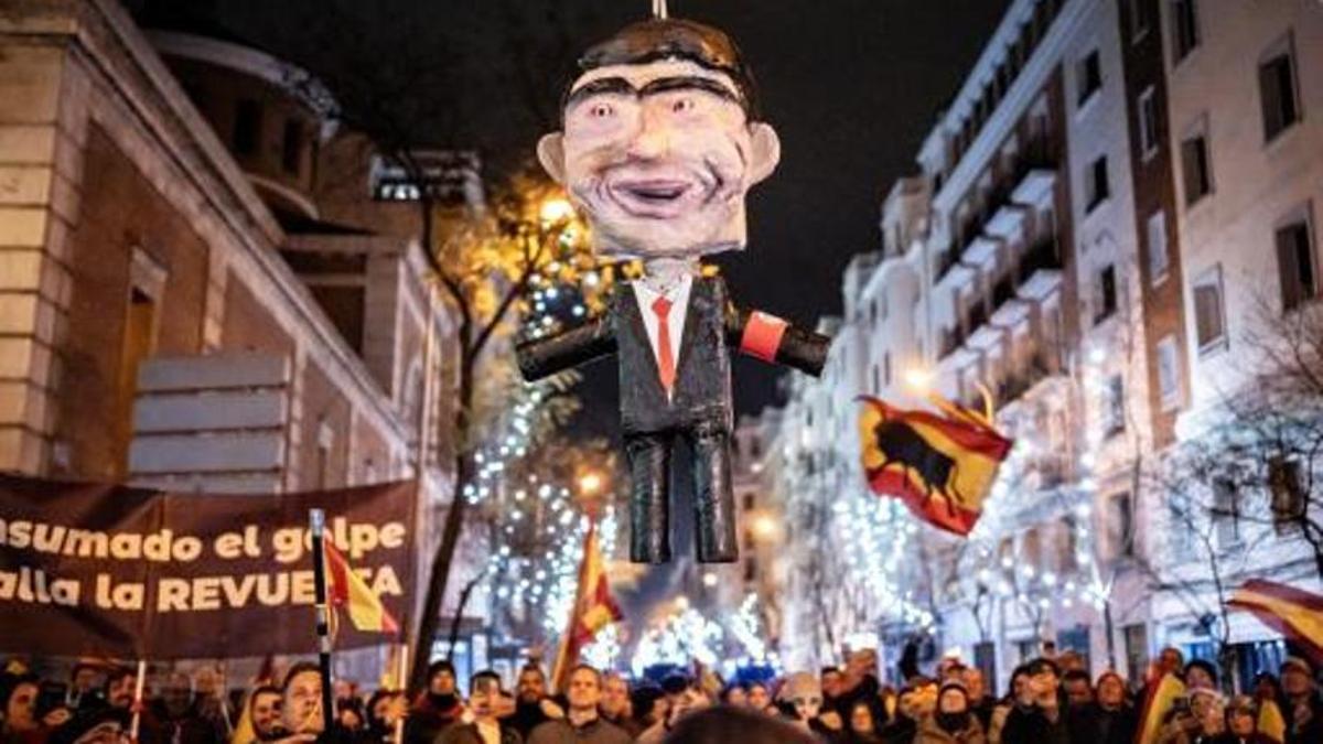 El muñeco que representaba a Pedro Sánchez es izado entre los manifestantes en la calle Ferraz el 31 de diciembre.