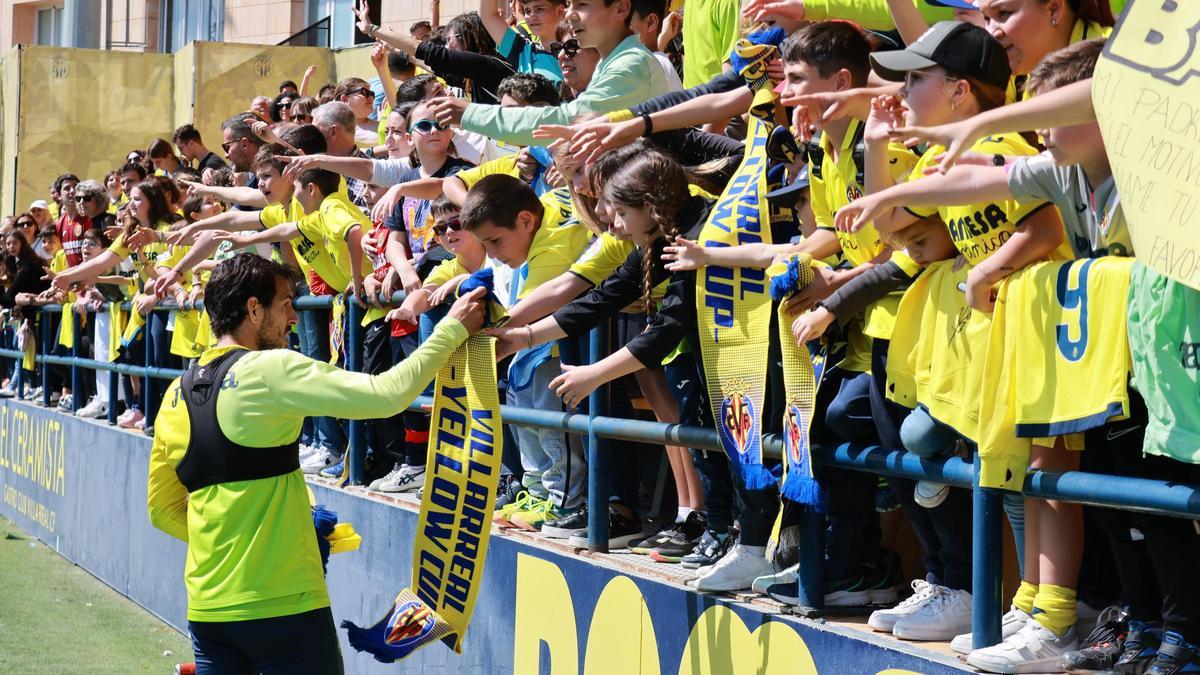 Dani Parejo, con varios aficionados del Villarreal CF firmando una bufanda, tras un entrenamiento.