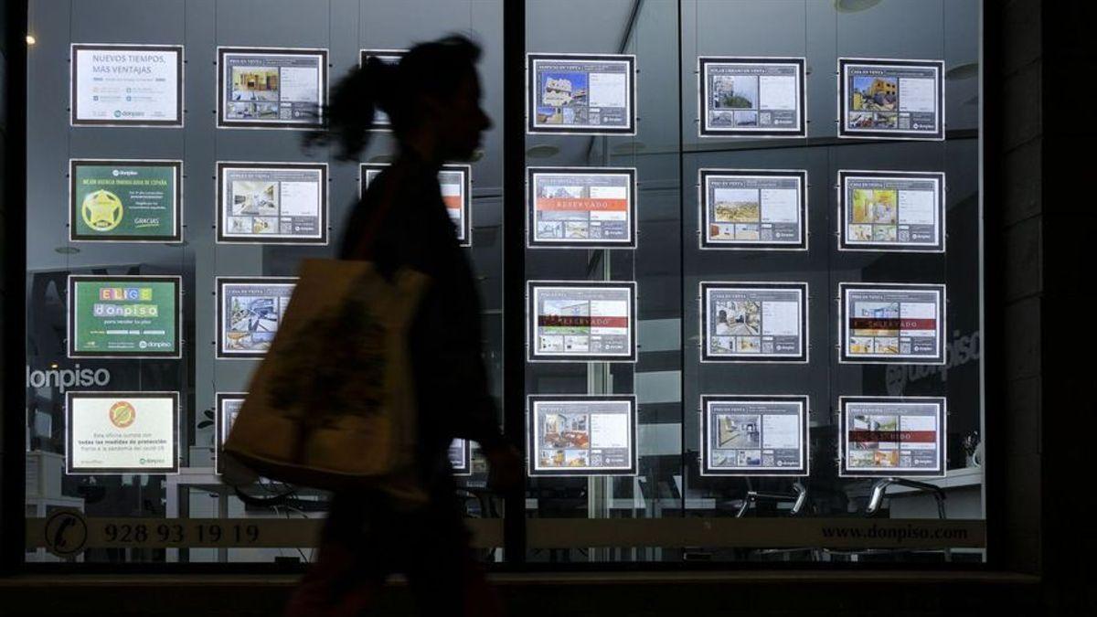 Una mujer pasa junto a anuncios de venta y alquiler de pisos.