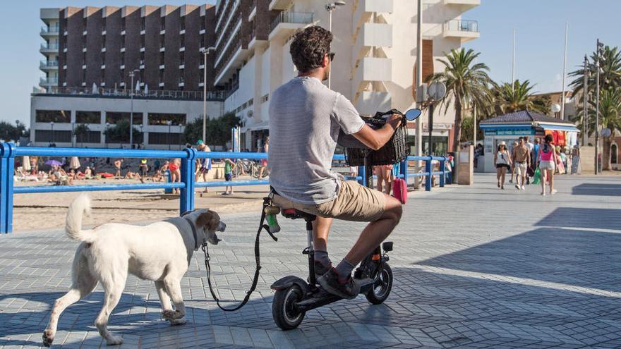 Un usuario, con una bicicleta eléctrica por la playa del Postiguet