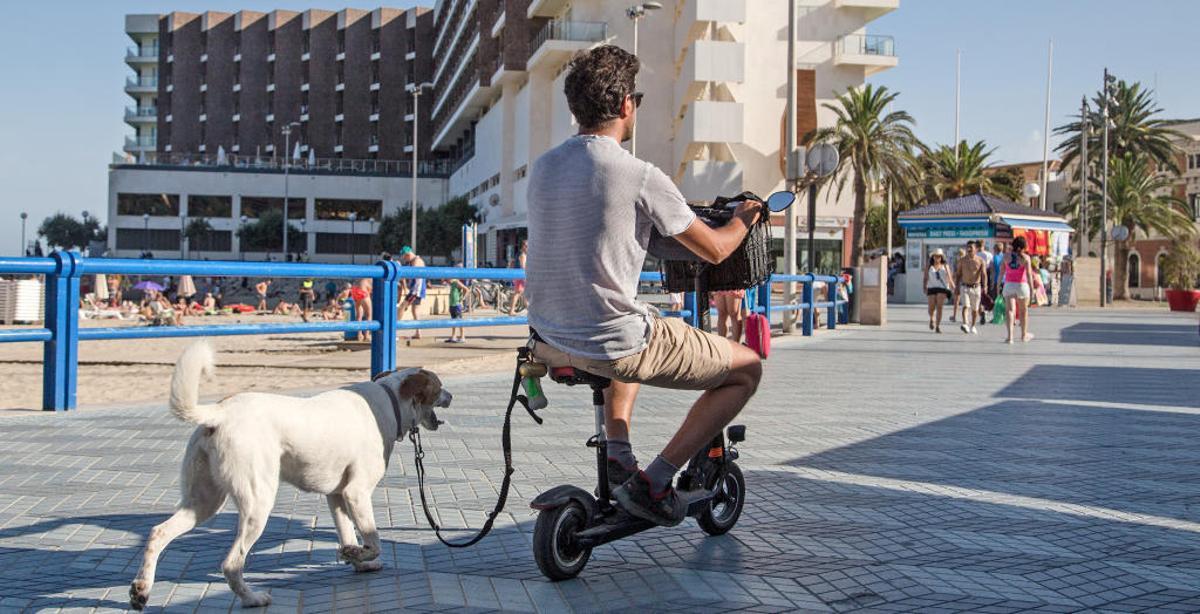Un usuario, con una bicicleta eléctrica por la playa del Postiguet