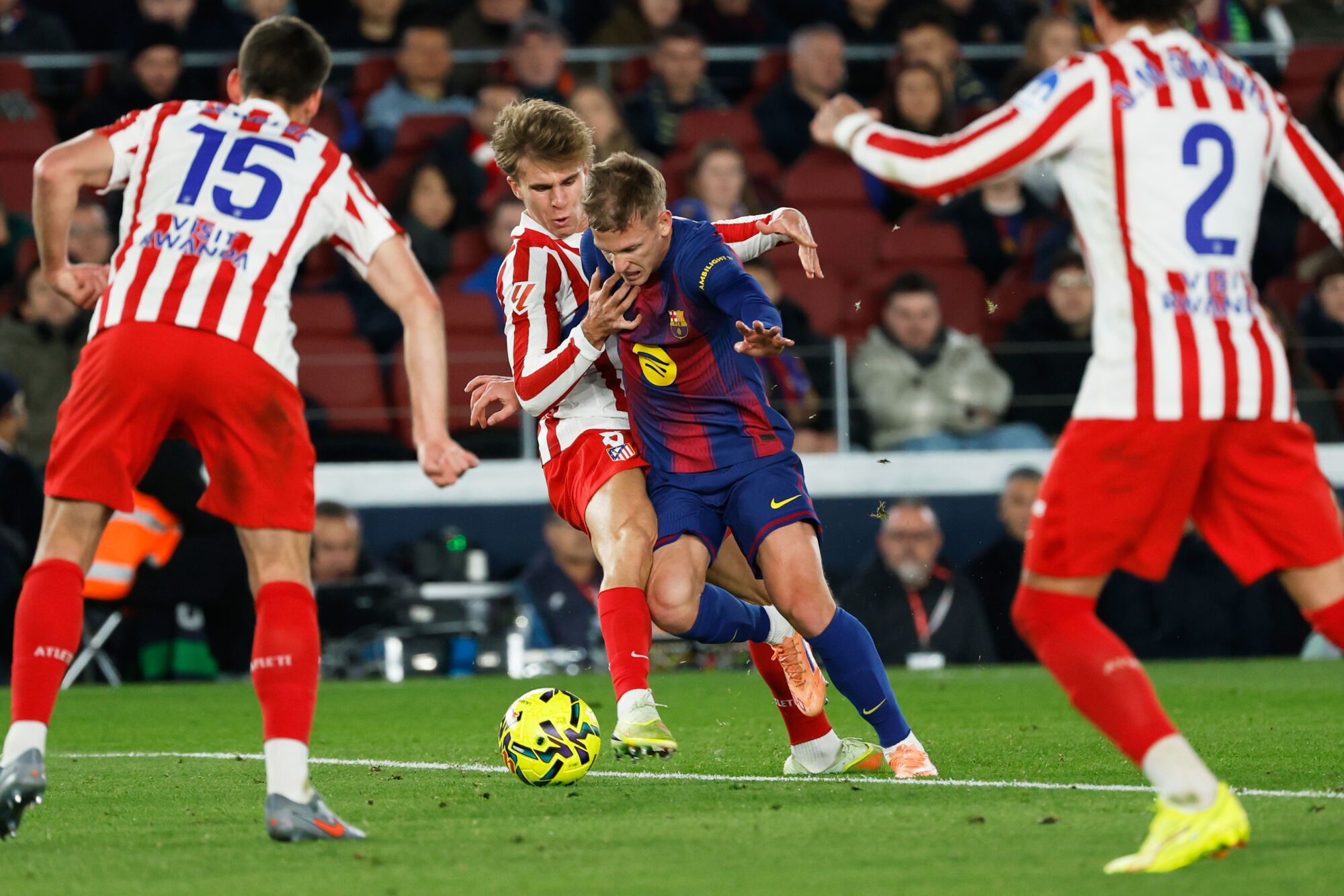Barcelona's Dani Olmo is tacked by Atletico Madrid's Pablo Barrios during a Spanish La Liga soccer match between Barcelona and Atletico de Madrid, in Barcelona, Spain, Tuesday, Dec.2, 2025. (AP Photo/Joan Monfort)