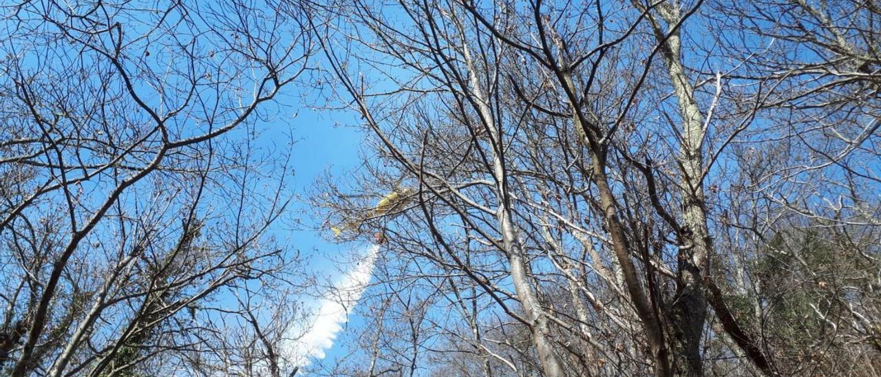 Un helicóptero vierte agua en el incendio de Fresnedo.| LNE