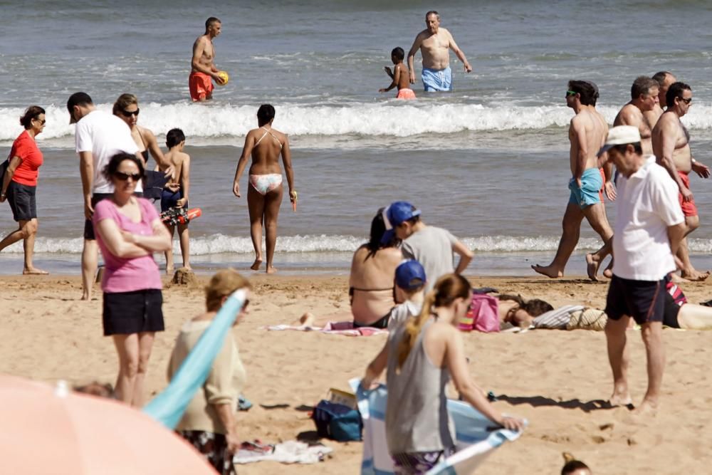 Gijoneses y visitantes se lanzan a la playa en una jornada calurosa.