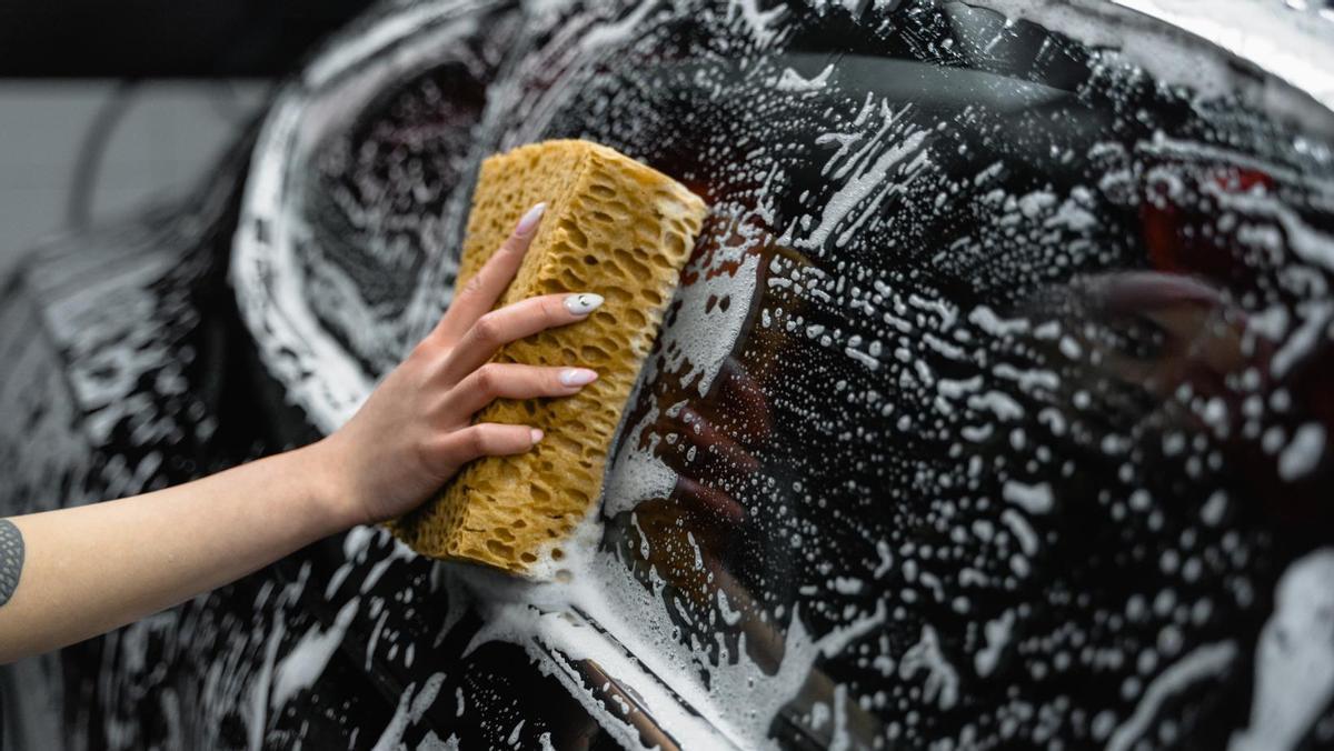Una mujer limpia su coche.