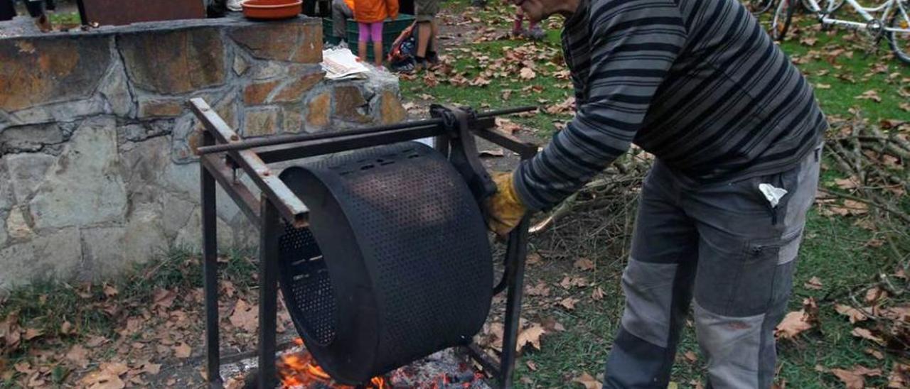 Alfredo Martínez asando las castañas con los comensales al fondo.