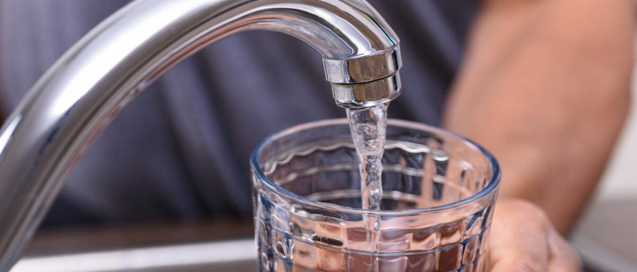 Un hombre vierte agua en un vaso.