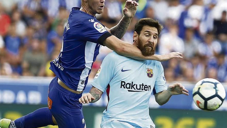 Carlos Vigaray sujeta por el cuello a Messi, ayer, en Mendizorroza. // David Aguilar