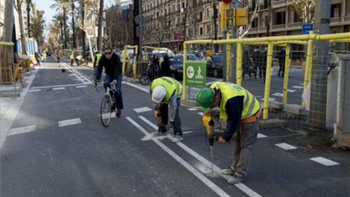 Dos operarios instalan los separadores del nuevo carril bici en la Diagonal en el tramo entre Francesc Macià y Aribau.