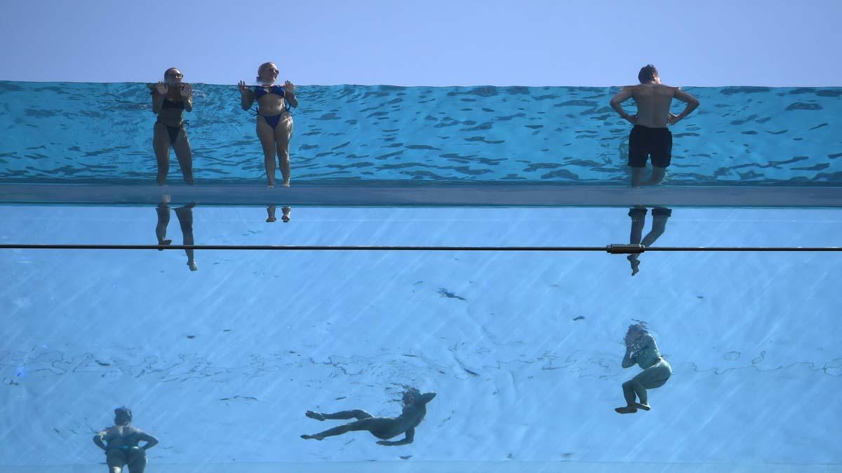Personas nadan en la Sky Pool, una piscina suspendida a 35 metros del suelo que une dos edificios de apartamentos en Embassy Gardens en Londres, Gran Bretaña a causa del calor extremo ya que el Reino Unido podría tener su día más caluroso registrado esta semana, con temperaturas pronosticadas que alcanzarán los 41 grados centígrados.