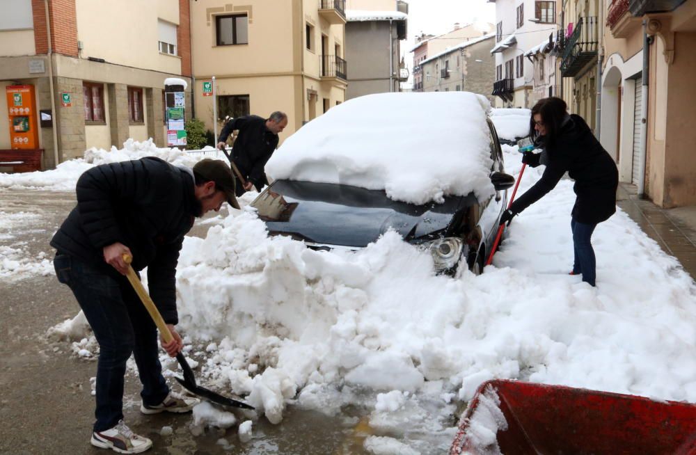 Tres persones intentant treure la neu acumulada dels seus vehicles a Camprodon, el 6 de febrer.