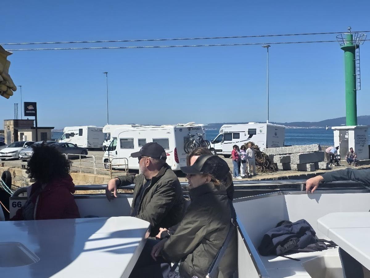 Viajeros de un catamarán observan las autocaravanas estacionadas en el puerto de O Corgo.