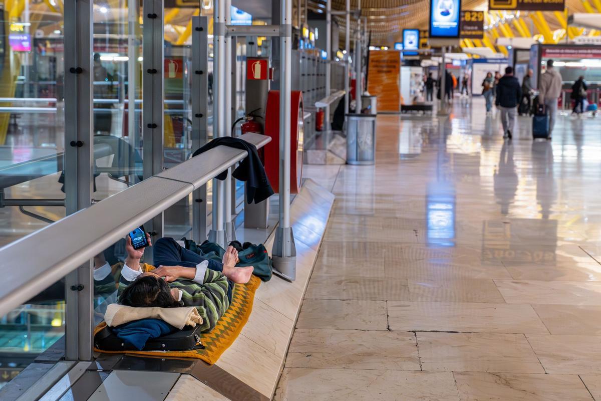 Una personas duerme en uno de los pasillos de la Terminal 4 del aeropuerto Adolfo Suárez Madrid Barajas.