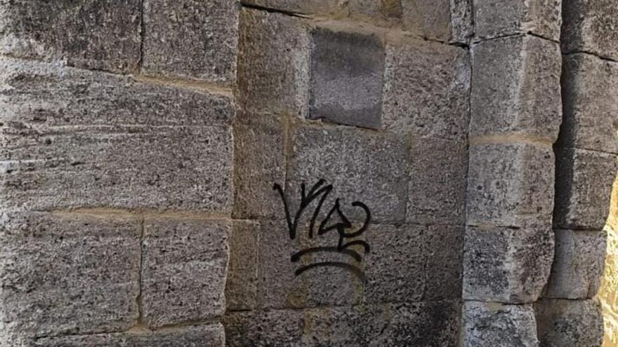 Arriba, pintada en el arco de Doña Urraca, ya borrada. A la izquierda, macetas destruidas en el parque de San Martín. | CEDIDA / V. R.