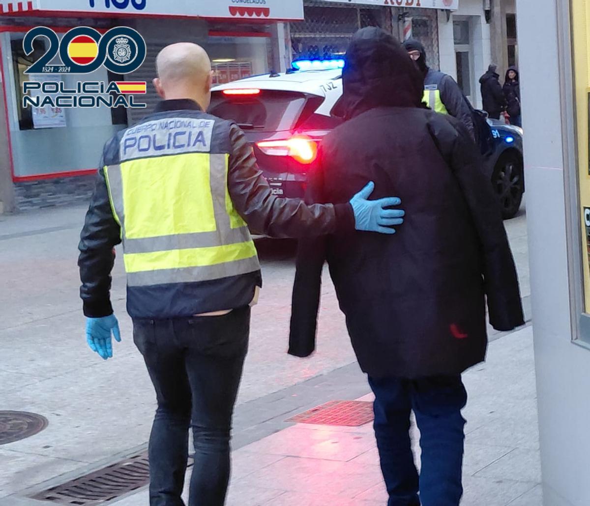 Un agente conduce al detenido al vehículo policial.