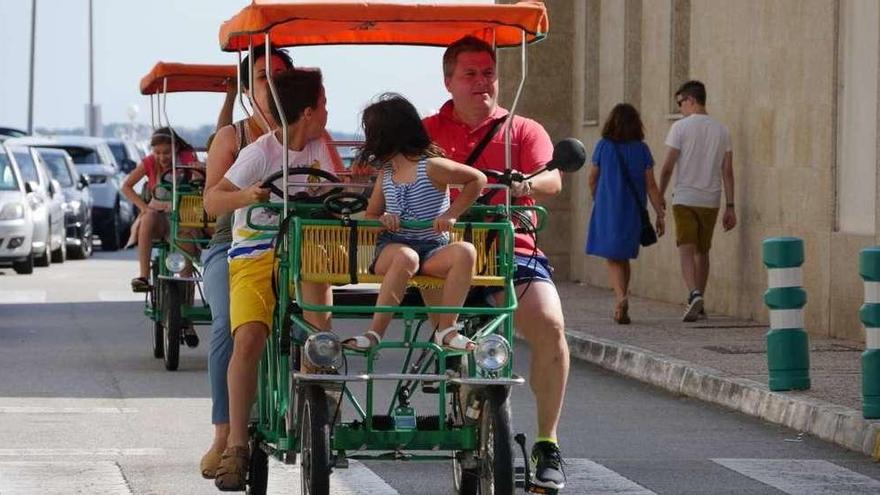 Una familia recorre O Grove, en un cuadriciclo a pedales, ayer. // Muñiz