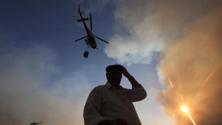 Un vecino observa el incendio y la actuación de los medios aéreos.