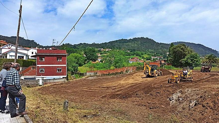 Dos vecinos, observando el trabajo de la maquinaria en la parcela del futuro aparcamiento. | S. Arias