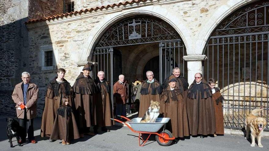 Devotos ataviados con sus capas pardas esperan la bendición de sus perros a la puerta de la iglesia.