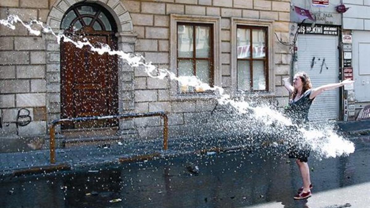 Una manifestante desafía al cañón de agua de la policía en Estambul.