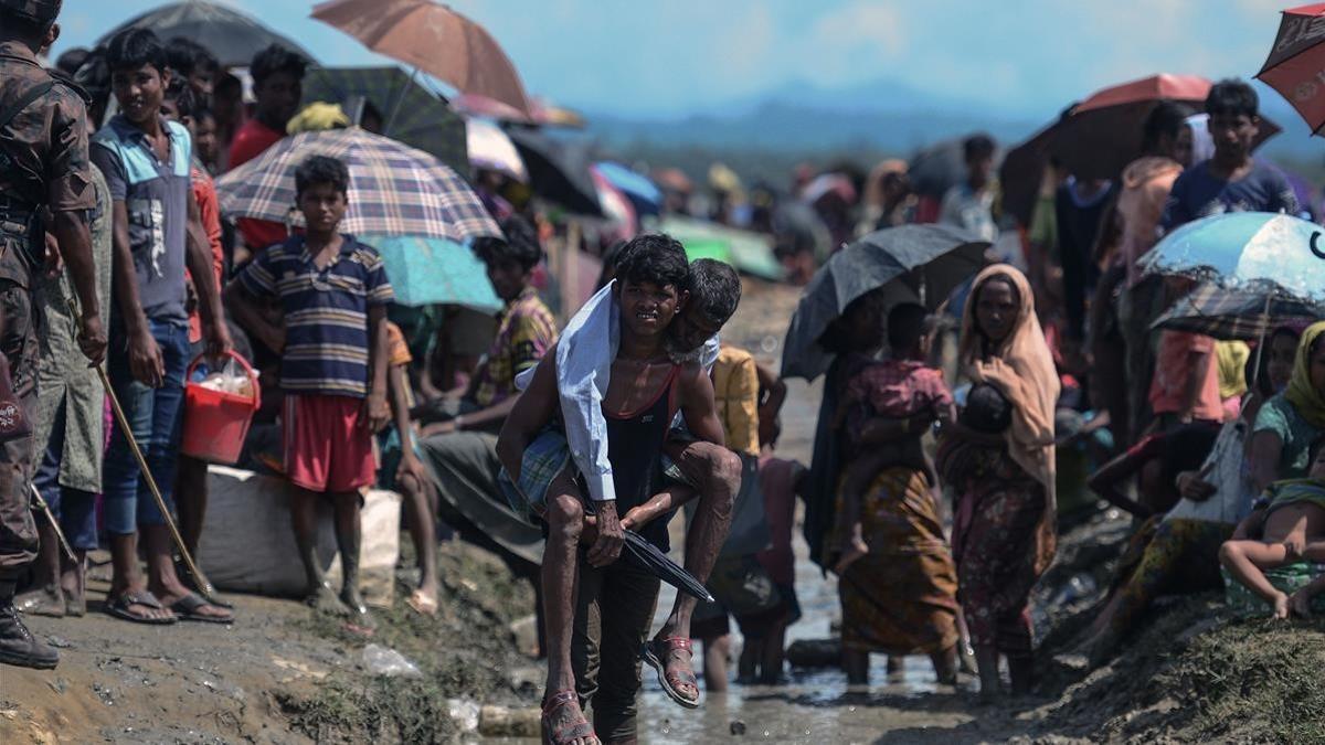 Un refugiado rohinyá lleva a cuestas a un anciano en Bangladés, cerca de la frontera con Birmania.