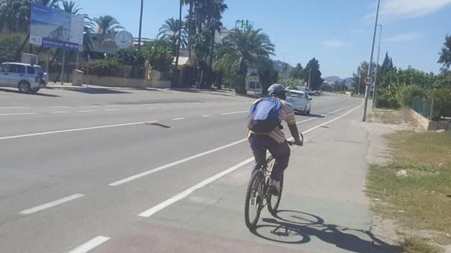 Un ciclista circula junto al carril bici en la zona de la entrada de la playa de Oliva.