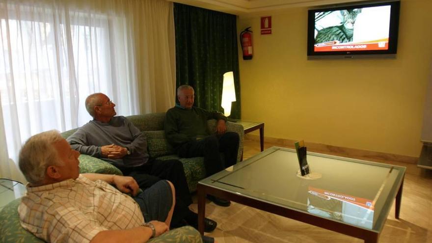 Turistas en un hotel ven la televisión.