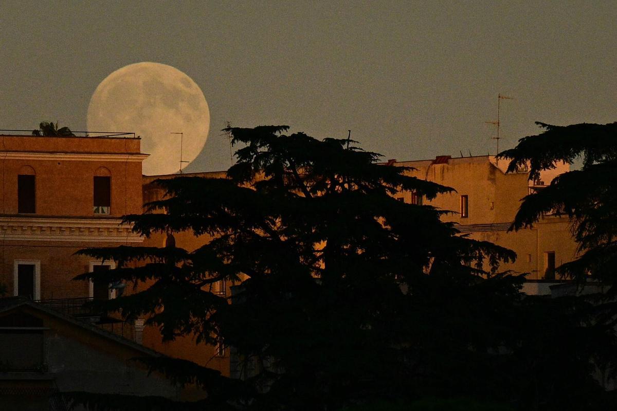 A full moon rises above old buildings in the historic center of Rome, on October 6, 2025. (Photo by Tiziana FABI / AFP)