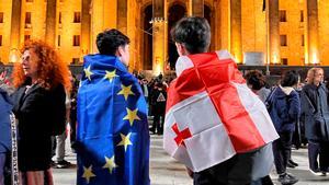 Dos jóvenes se cubre con las banderas de la Unión Europea y Georgia durante la protesta en Tbilisi por la Ley de agentes secretos..
