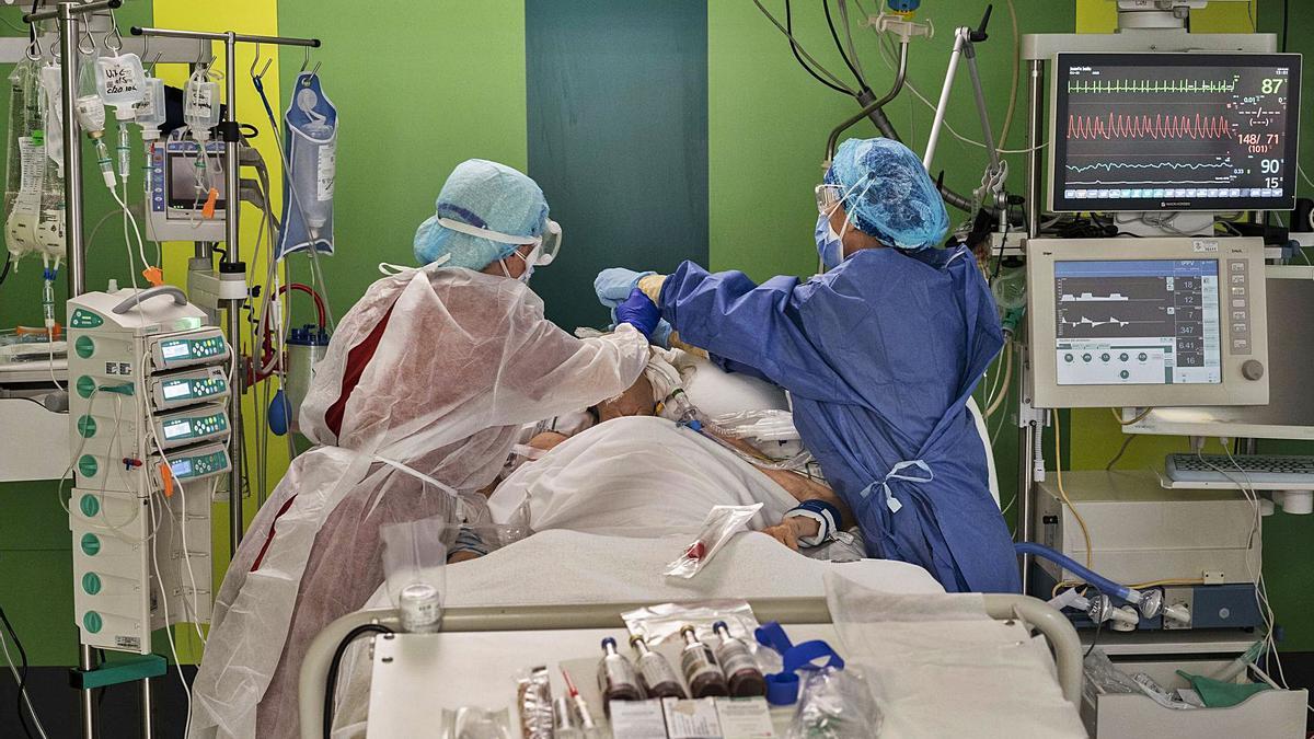 Dos sanitarios atienden a un enfermo de covid ingresado en la UCI del Hospital General de València. | GERMÁN CABALLERO