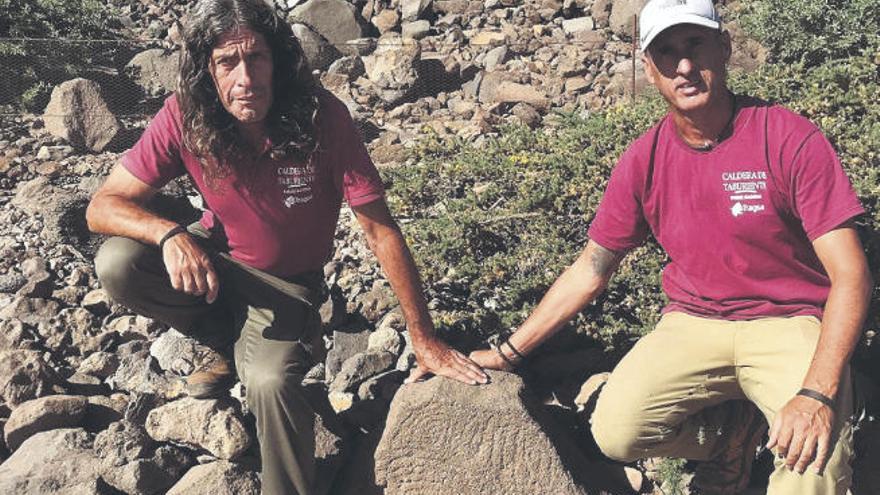 Antonio Rodríguez y Álvaro Rodríguez posan con el grabado benahoarita que encontraron en un sendero de la Caldera de Taburiente.