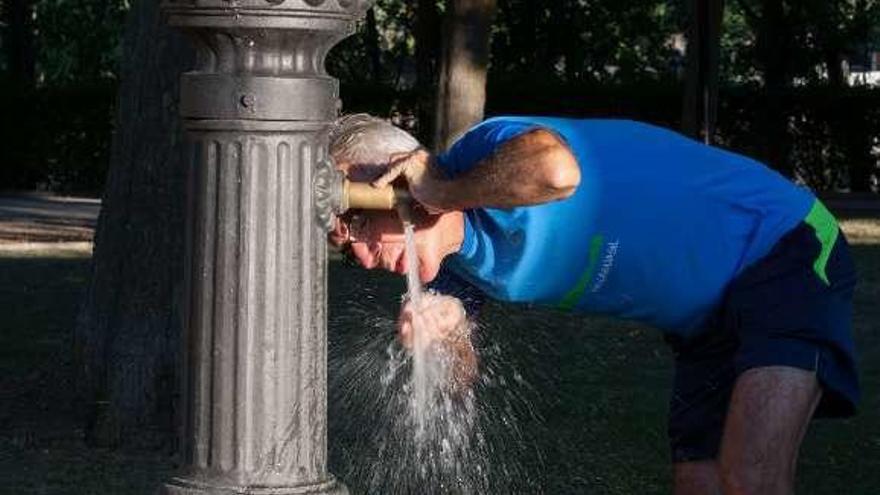 Un hombre se refresca en la fuente.