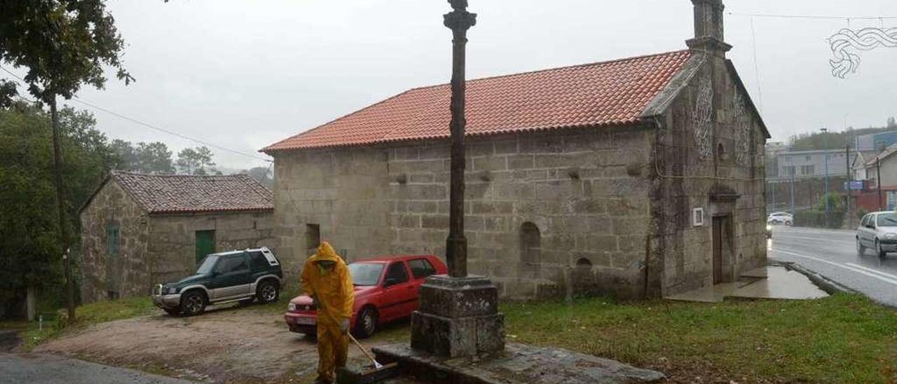 Un operario limpia el entorno de la capilla de San Simón, en la parroquia de Baión. // Noé Parga