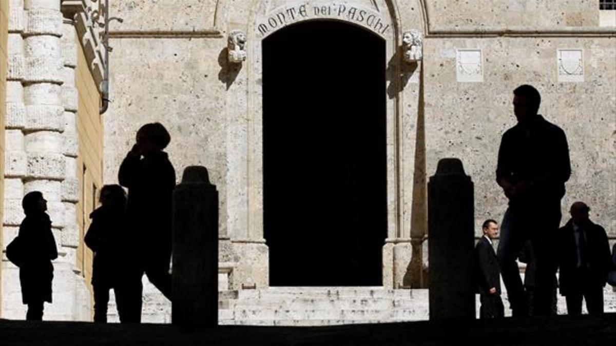 Peatones pasan por delante de la puerta principal de la sede central de Monte dei Paschi, en Siena.