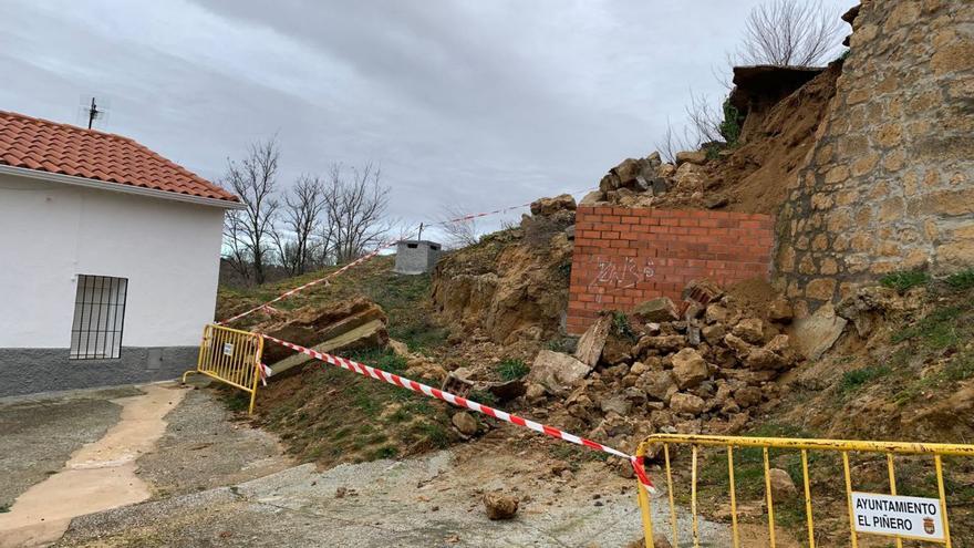 Derrumbe del muro perimetral de la iglesia en El Piñero, con los cascotes y la tierra a la misma puerta de una vivienda. | Cedidas