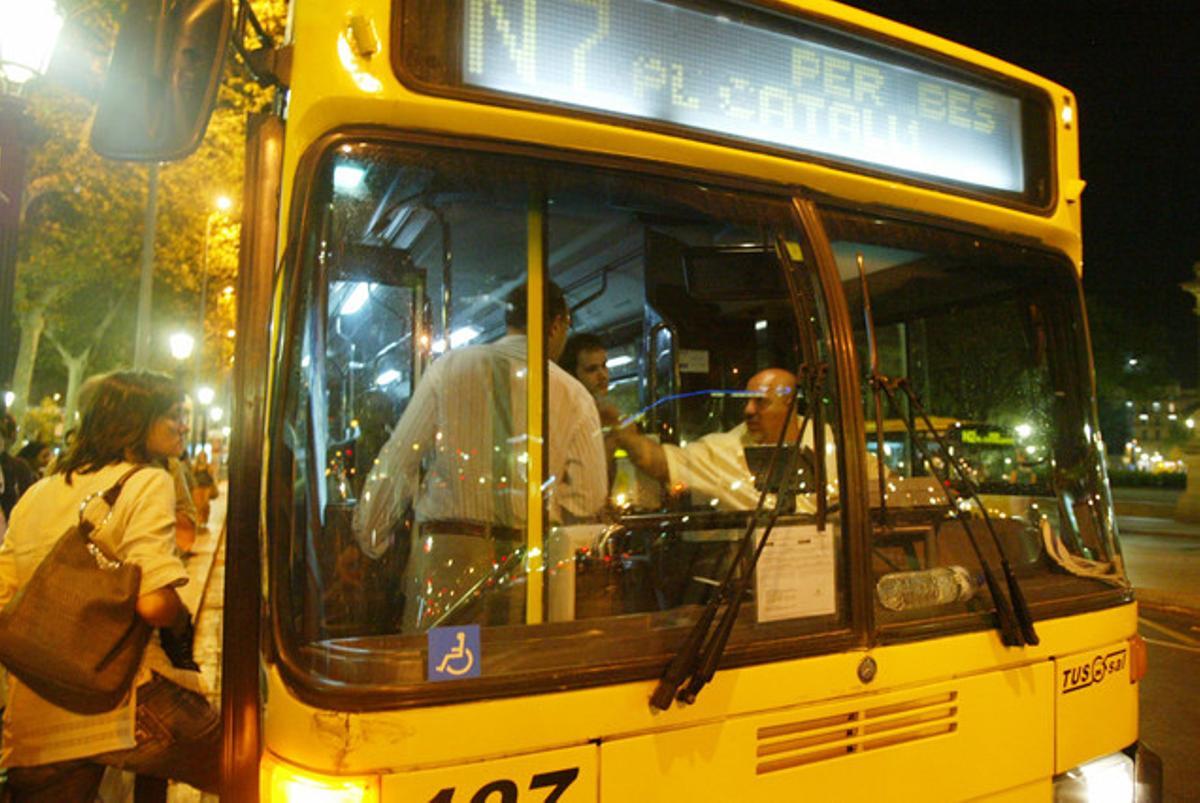 Usuaris del Nitbus pugen a un vehicle a la plaça de Catalunya.