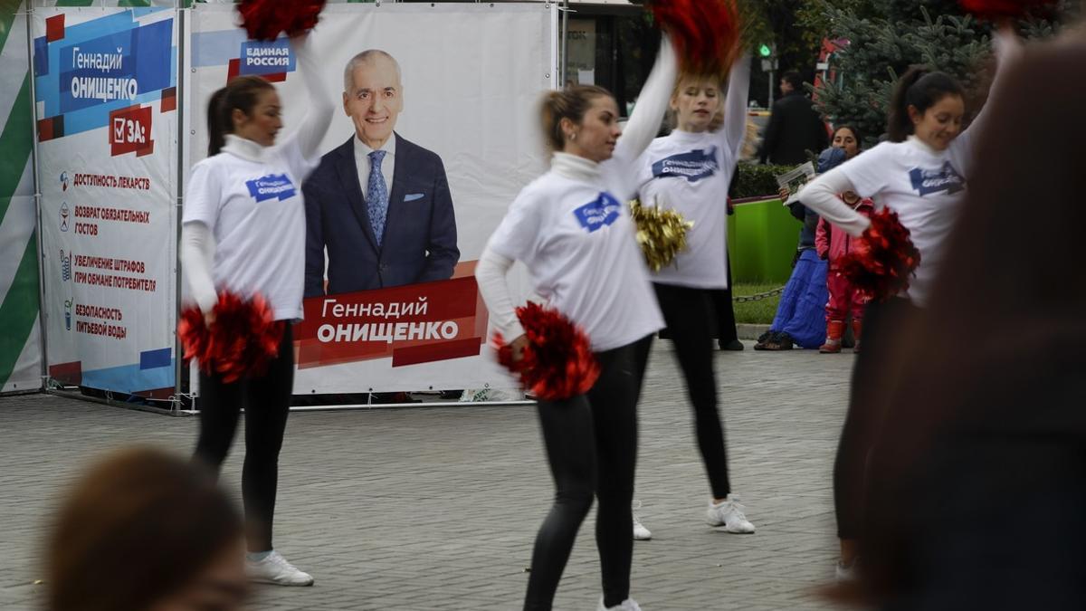 Jóvenes voluntarias pro-Putin bailan ante un cartel electoral de Rusia Unida.