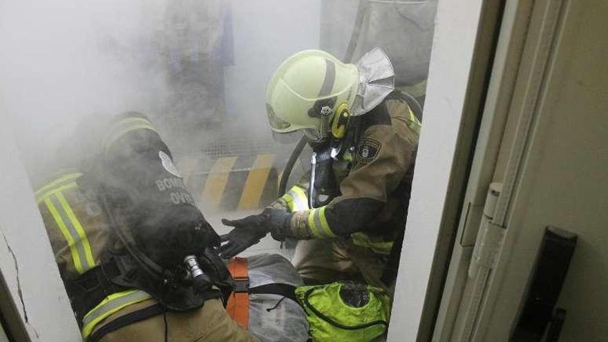 Los efectivos en una sala llena de humo iniciando el rescate del herido de trapo.