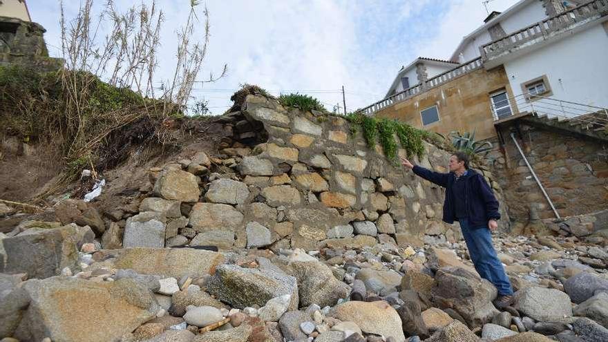 Un vecino muestra los daños causados por el mar al muro de cierre de su vivienda. // G. Santos