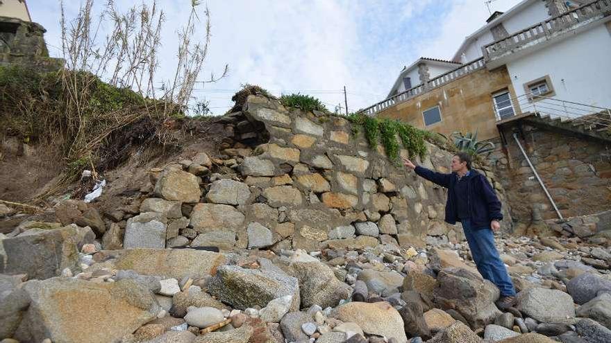 Un vecino muestra los daños causados por el mar al muro de cierre de su vivienda.  // G. Santos